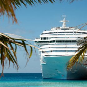 tall white cruise ship sailing on light blue sea